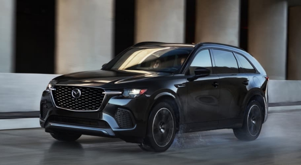 A black 2025 Mazda CX-70 for sale driving on a wet road.