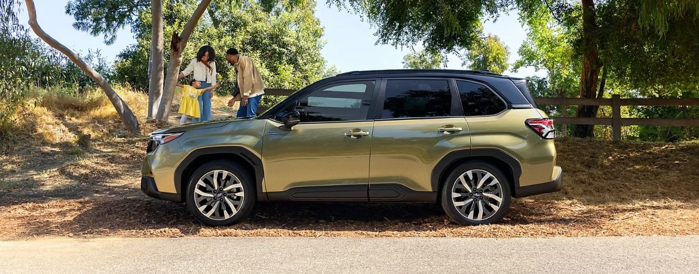 A green 2025 Subaru Forester Hybrid for sale in Rhinebeck parked near a family.