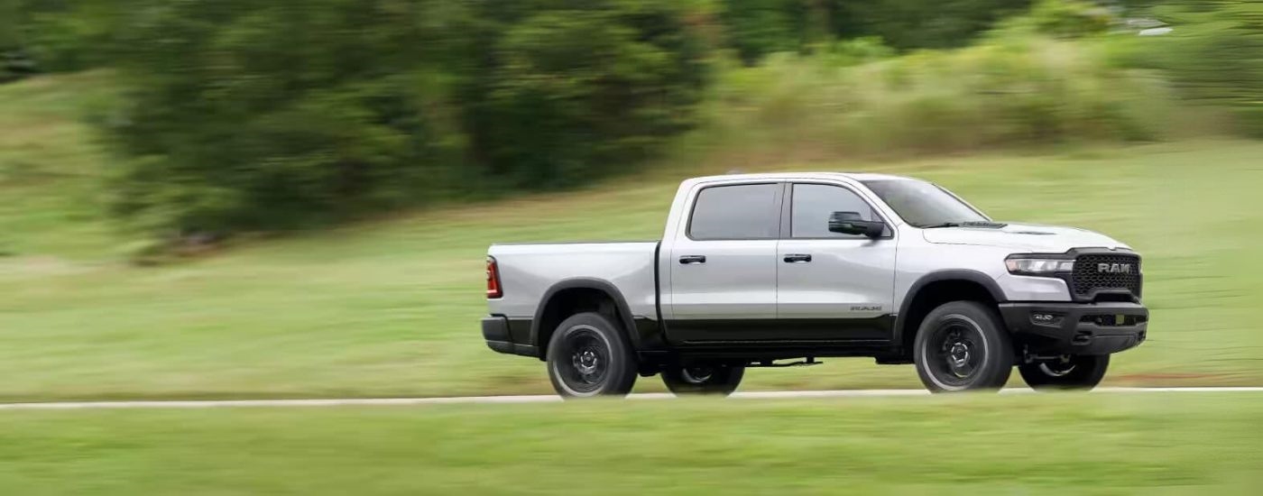 Silver 2025 Ram 1500 driving on a grass-lined road