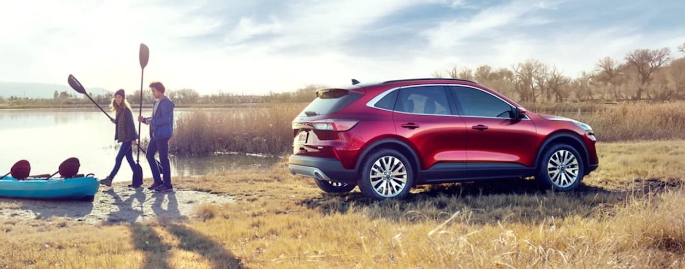 People carrying oars from a red 2020 Ford Escape.