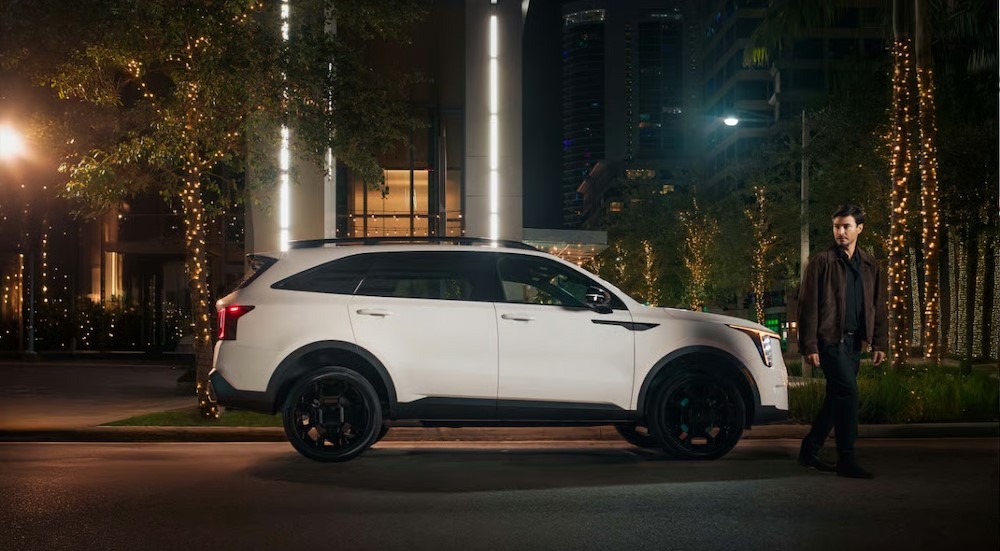 A white 2025 Kia Sorento parked near a man at night.