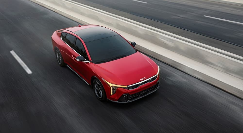 Aerial view of a red 2025 Kia K4 driving on a highway.