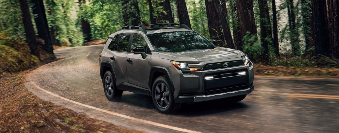A grey 2026 Toyota RAV4 driving on a winding road.