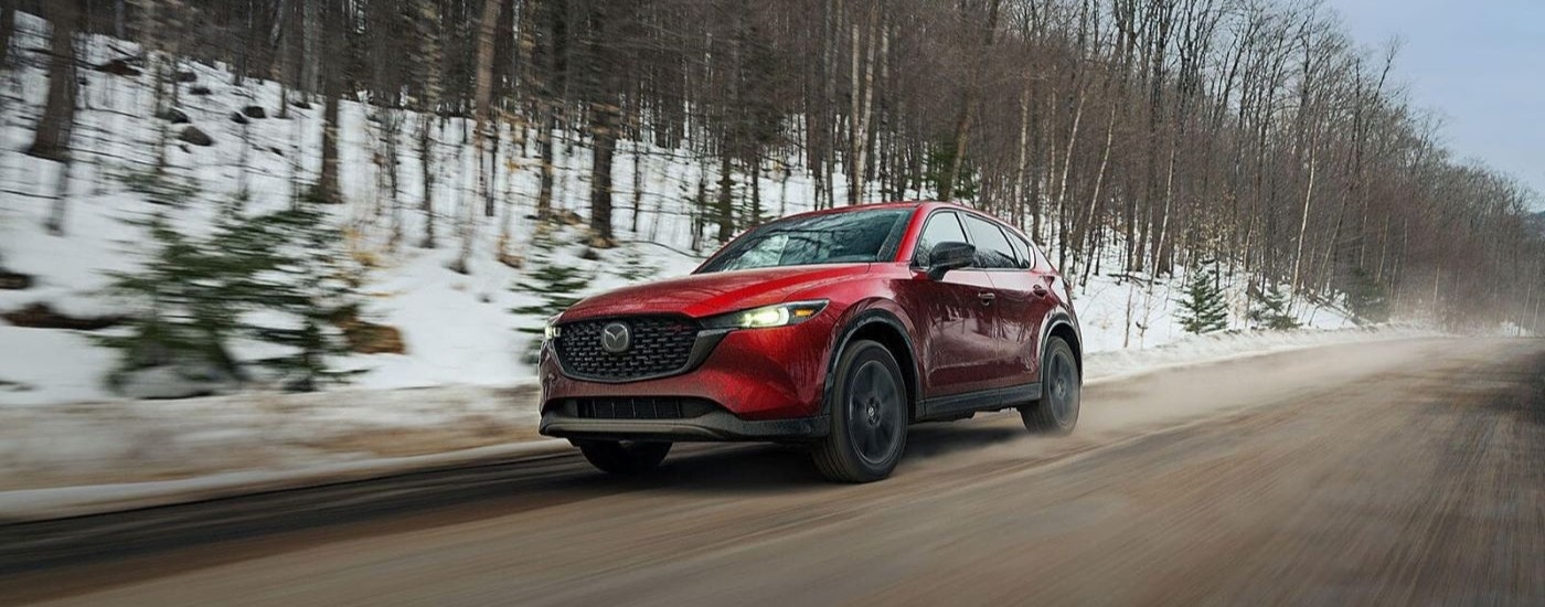 Side of a silver 2025 Mazda CX-5 driving down a street.