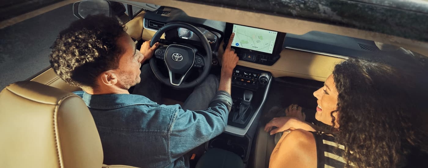 Man and woman driving in a 2025 Toyota RAV4 through a city