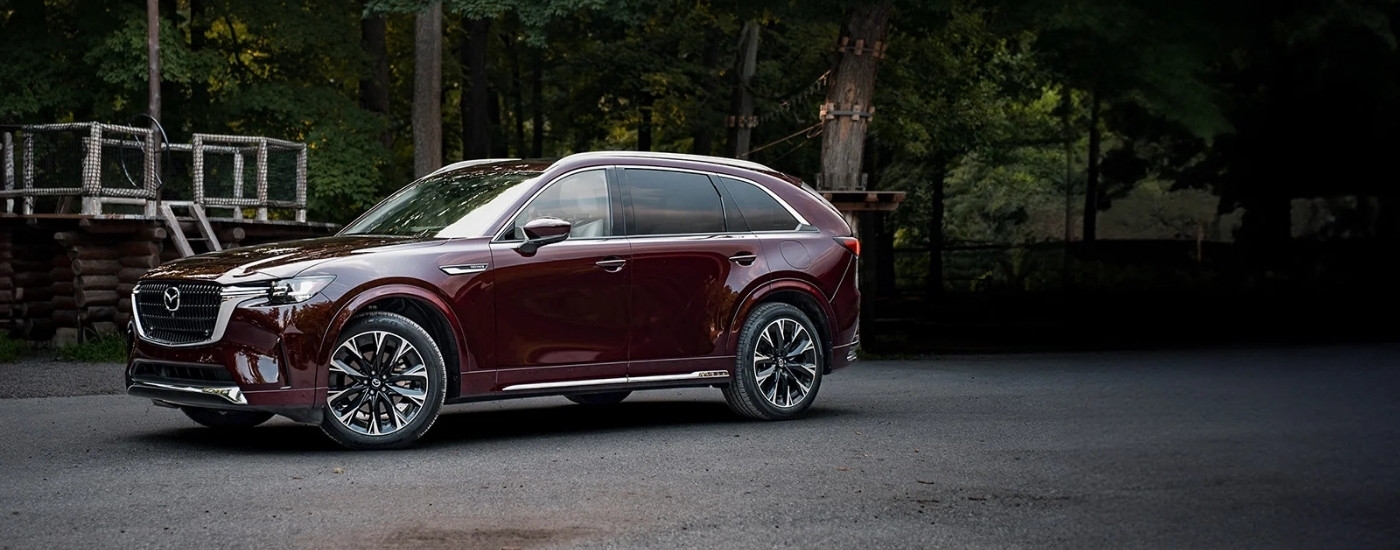 A purple 2024 Mazda CX-90 parked at a adventure course.