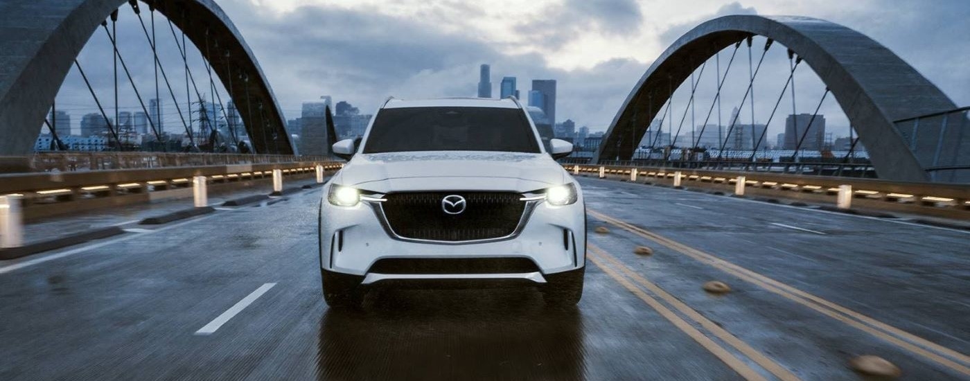 A white 2024 Mazda CX-90 for sale near Hialeah driving over a bridge.