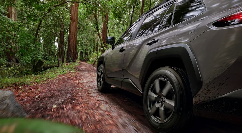 Side of a 2026 Toyota RAV4 driving down a muddy forest road