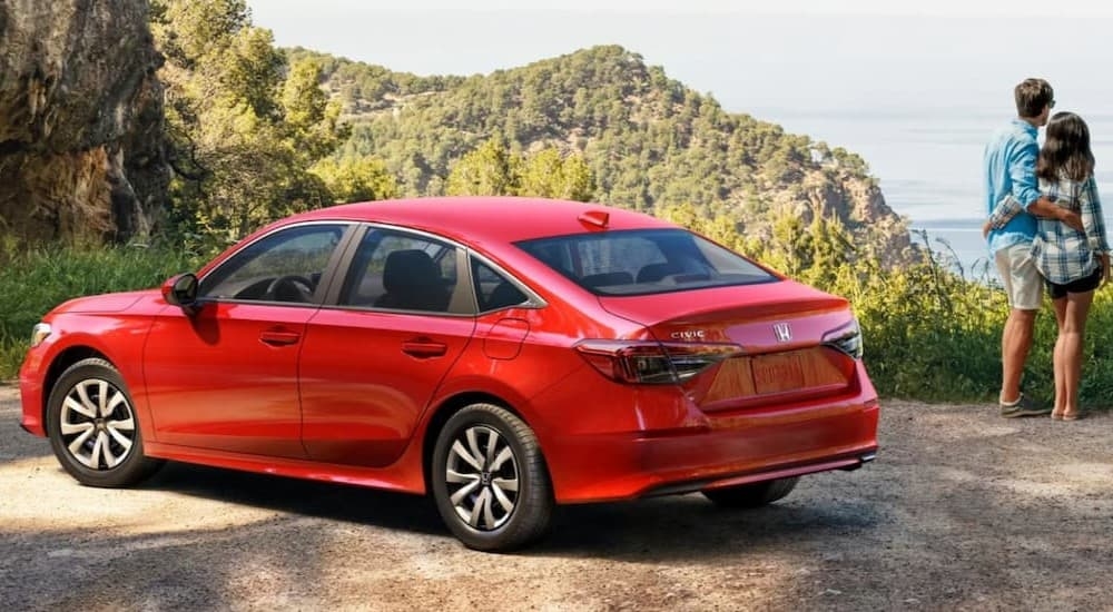 A red 2026 Honda Civic parked near a couple on a cliff.