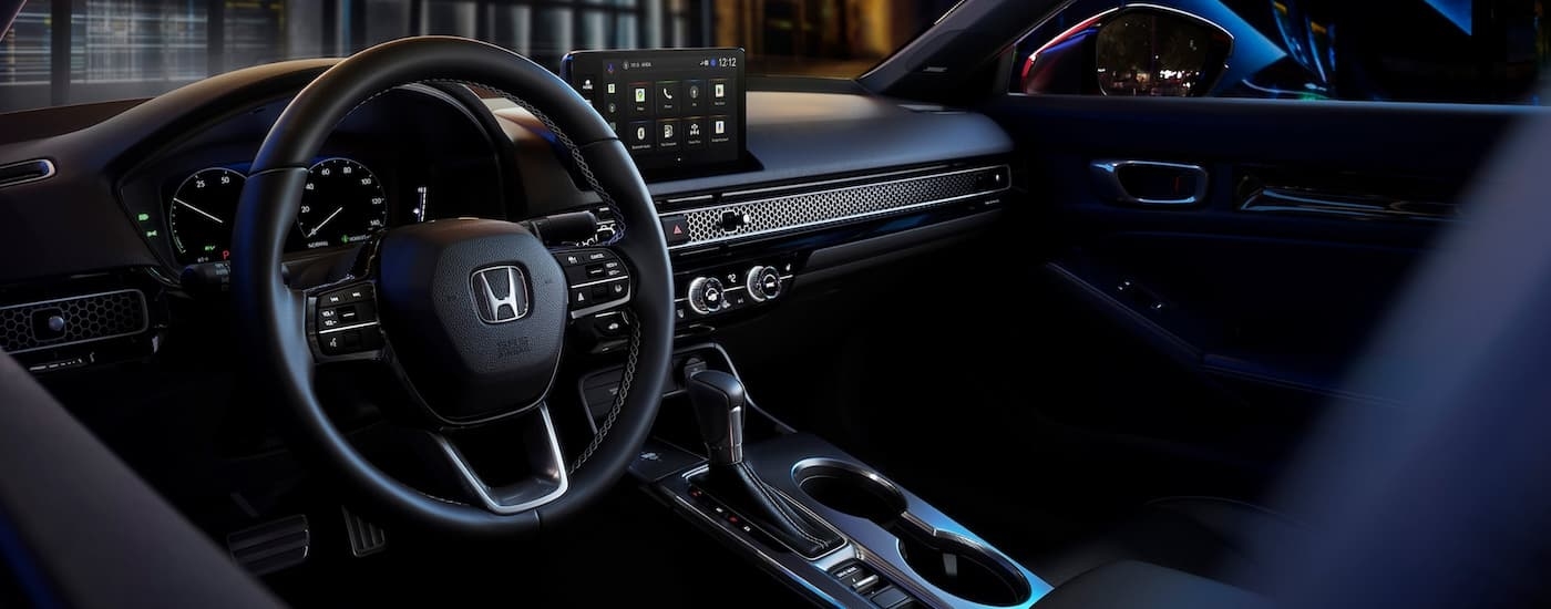 Wheel and infotainment screen in the interior of a 2026 Honda Civic Sport Touring Hybrid.