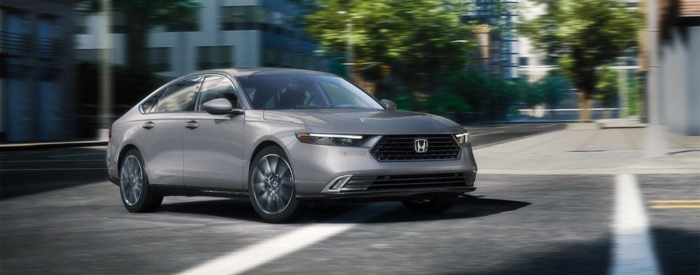 Grey 2025 Honda Accord Touring Hybrid crossing a city street.