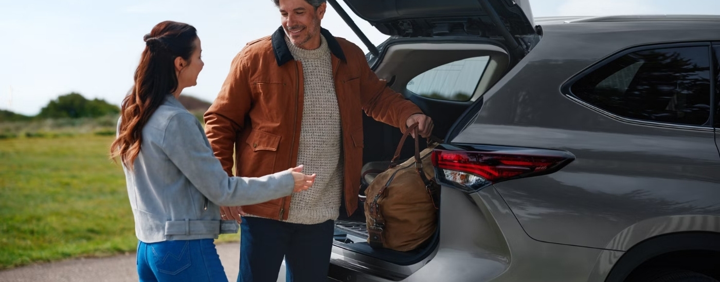 Person loading a bag in a 2025 Toyota Highlander Hybrid XLE Nightshade