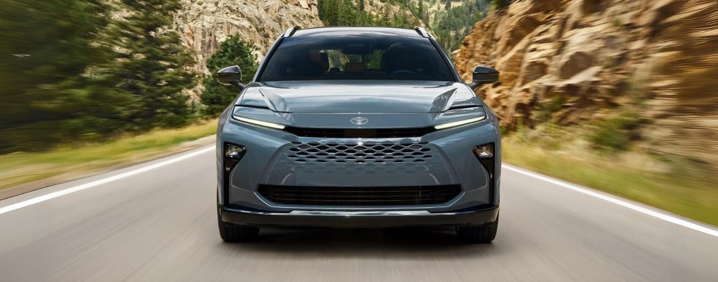 Front of a silver 2025 Toyota Crown Signia driving down a road.