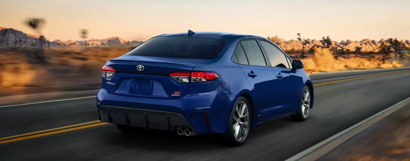 Rear of a blue 2025 Toyota Corolla SE driving down a road.