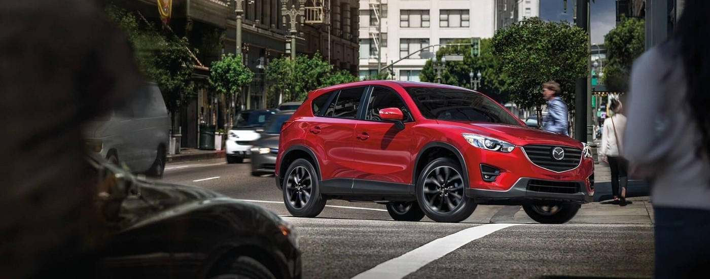 Red 2016 Mazda CX-5 driving through an intersection
