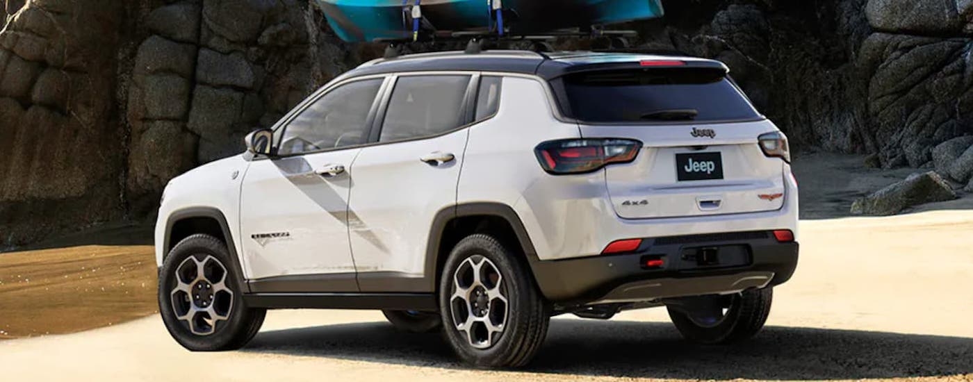 Rear of a white 2025 Jeep Compass parked off-road.