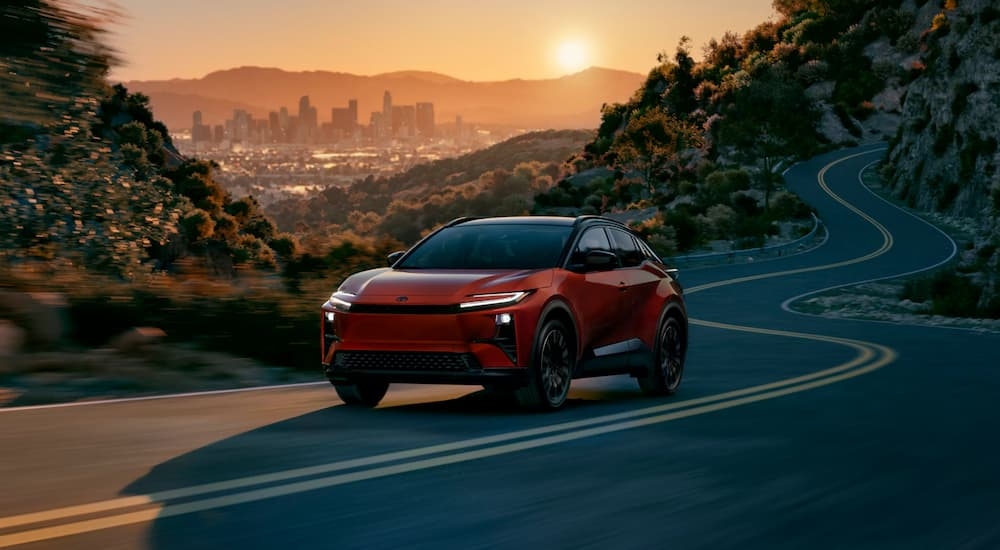 Red 2025 Toyota C-HR driving down a wavy road from a Toyota dealer near Leitchfield.