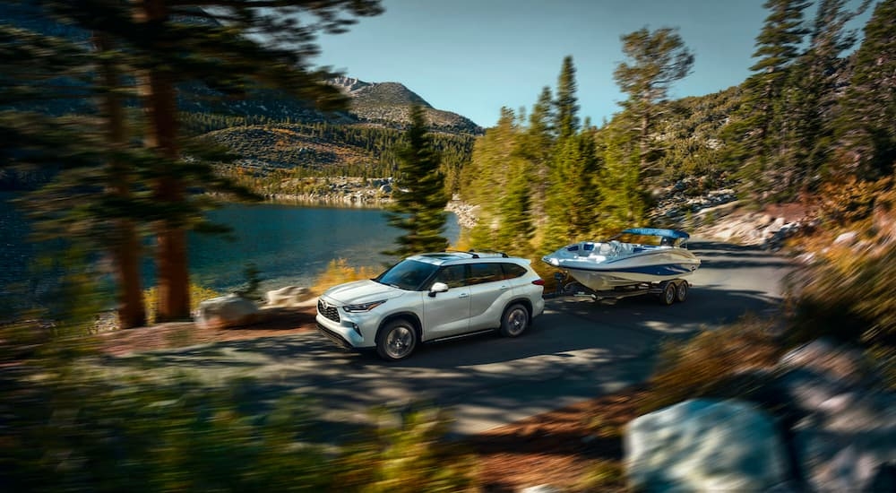 White 2025 Toyota Highlander driving around a bend.