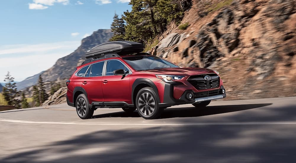 Red 2025 Subaru Outback driving on a winding road