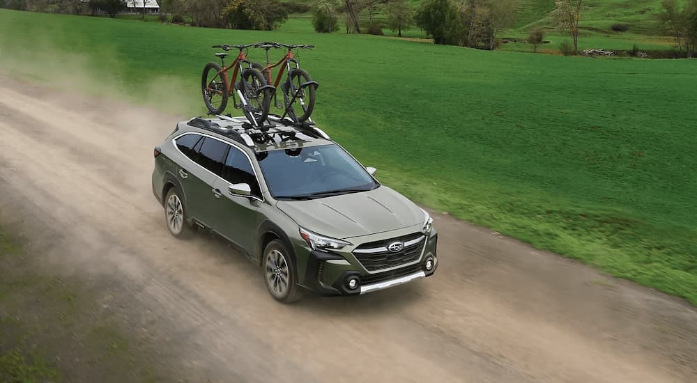 Green 2025 Subaru Outback driving on a dirt road