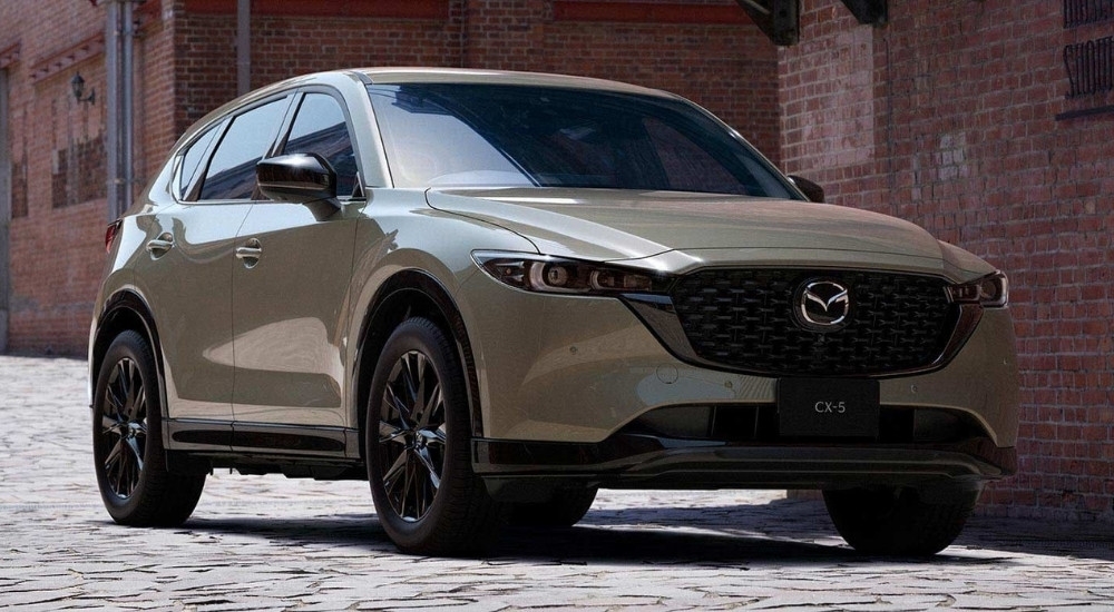 Grey 2025 Mazda CX-5 for sale near The Woodlands parked in front of a brick building