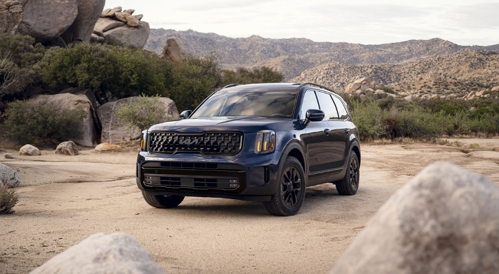 A blue 2025 Kia Telluride SX Prestige X-Line for sale parked off-road.