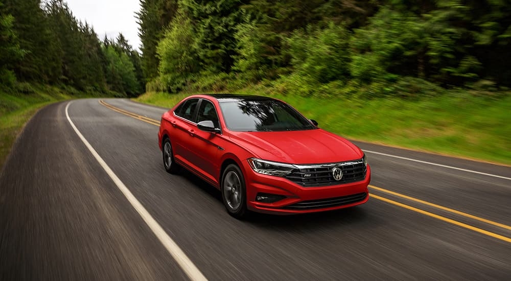 Red 2021 Volkswagen Jetta driving in a winding road