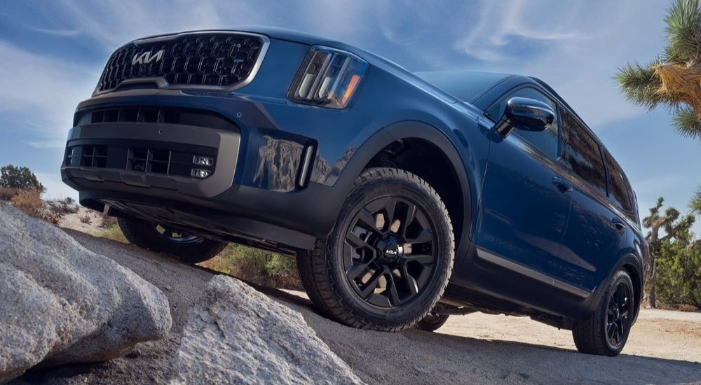 Blue 2025 Kia Telluride driving up a hill.