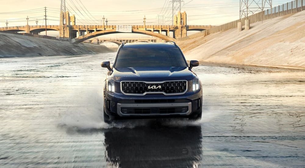 Front of a black 2025 Kia Telluride for sale driving in a city.