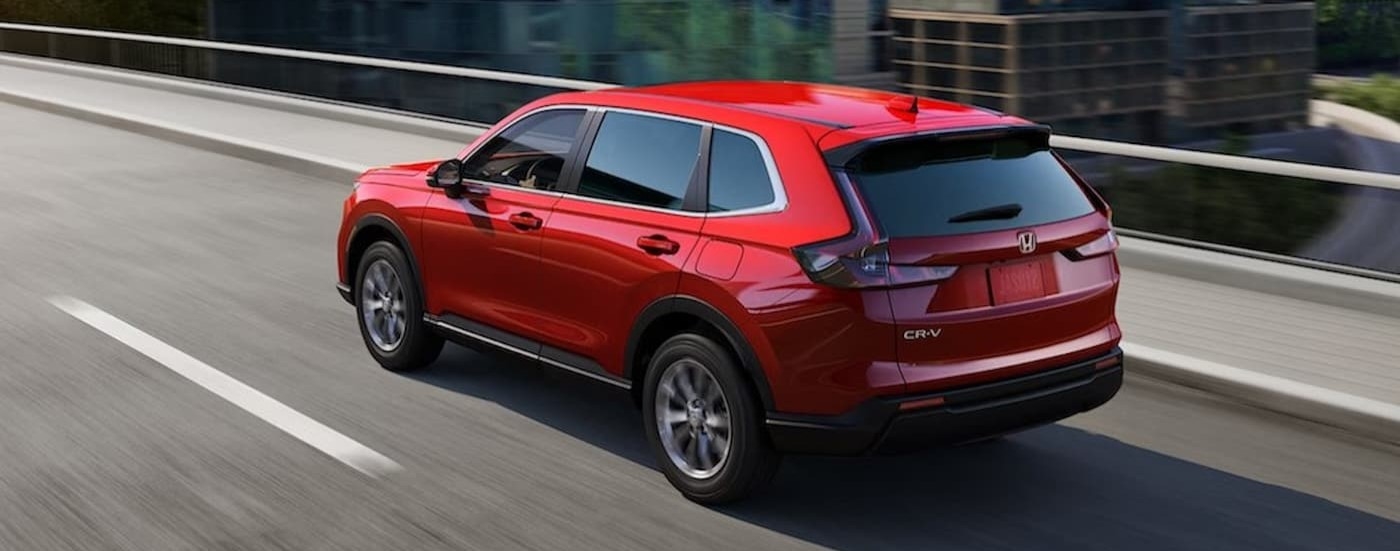 A red 2023 Honda CR-V driving on a bridge.