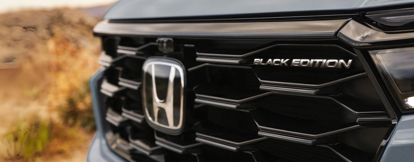 Close-up on the grille and badge of a grey 2025 Honda Pilot.
