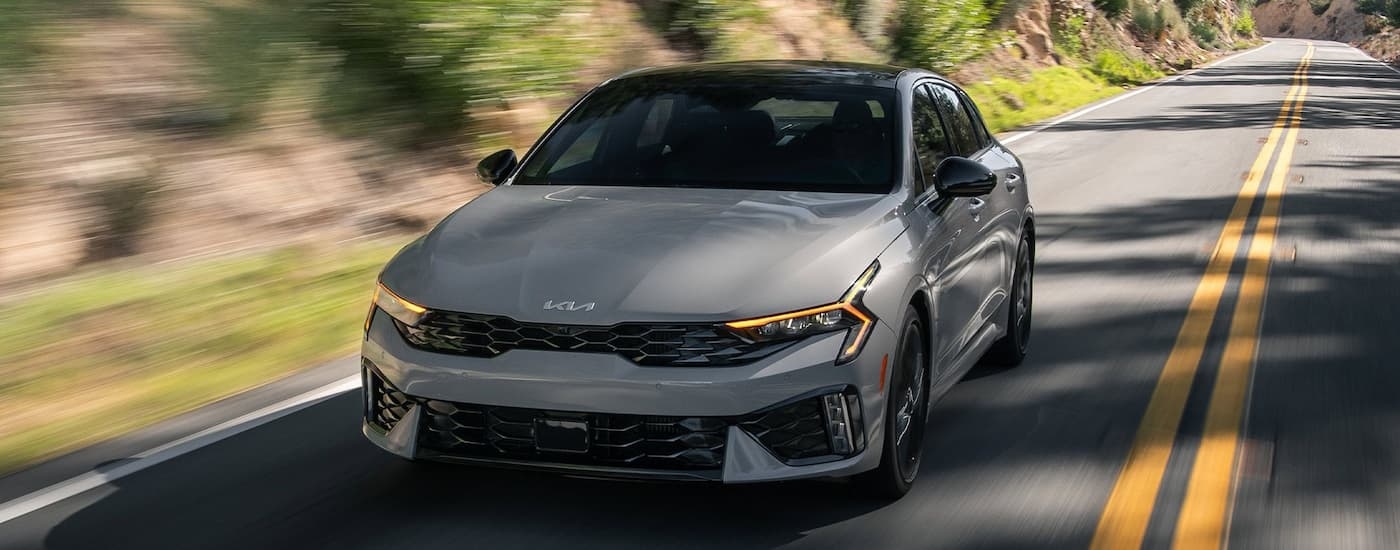 Grey 2025 Kia K5 driving from a Kia dealer near Pearland.