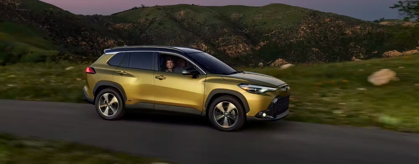 Yellow 2023 used Toyota Corolla Cross Hybrid XSE for sale near Bennington driving past hills