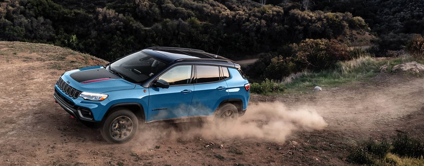 Blue 2025 Jeep Compass for sale near Kingston driving off-road.