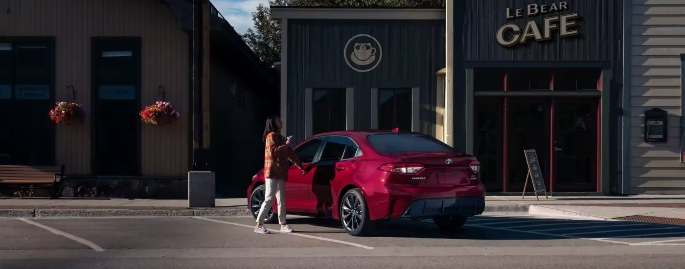 Red 2023 Toyota Corolla Hybrid SE parked in front of a coffee shop