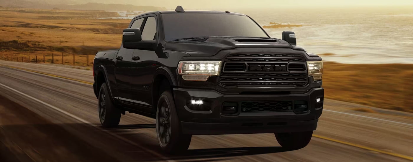 Black 2025 Ram 3500 driving down an open road.