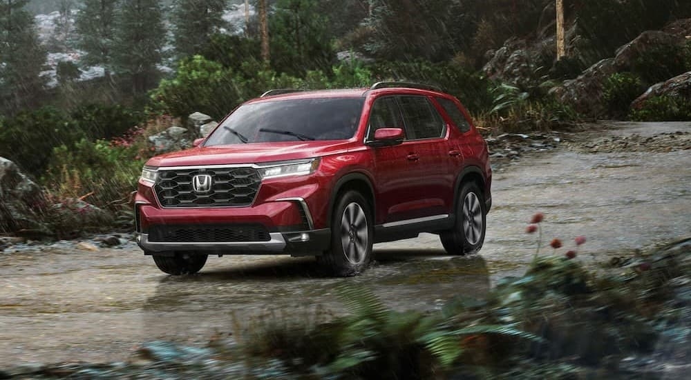 A red 2025 Honda Pilot driving on a rainy day.