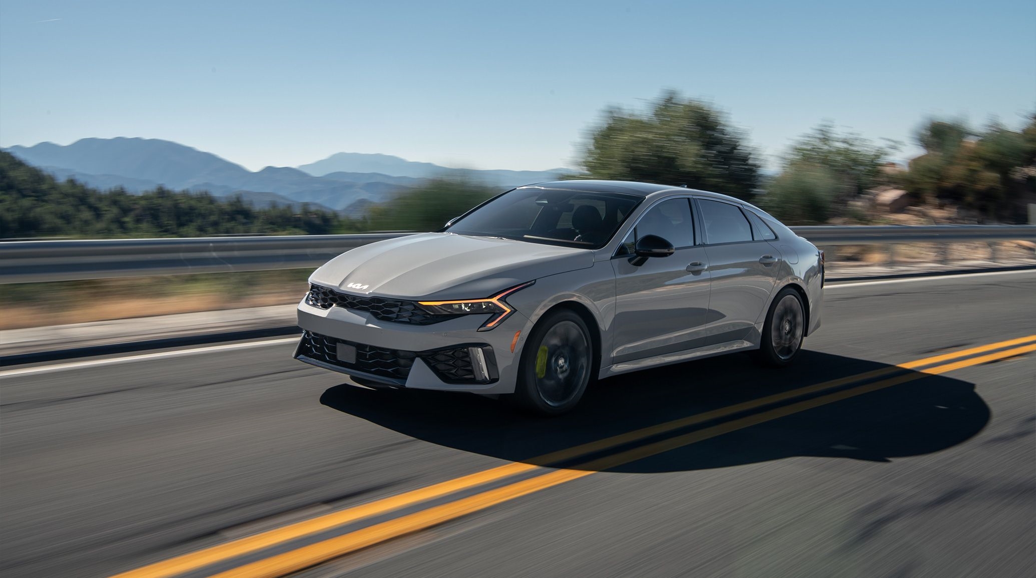 Grey 2025 Kia K5 driving from a Kia dealer near Pearland.