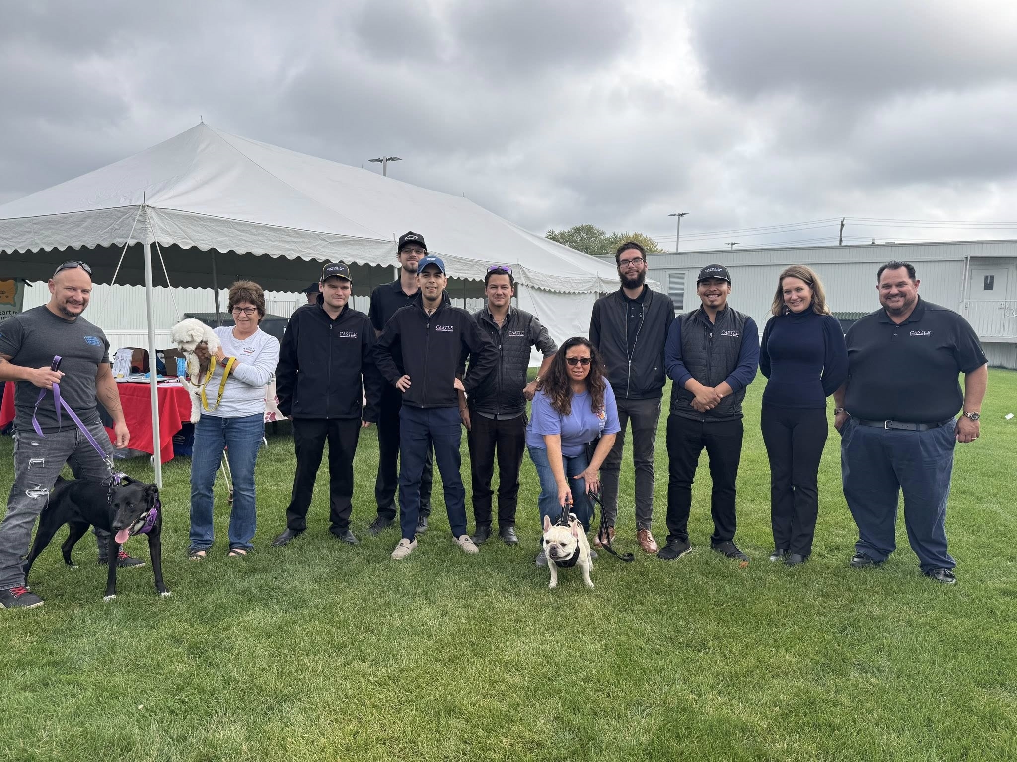 2025 Fetch A Friend Pet Adoption Event at Castle Subaru McHenry. Volunteers shown standing in the lawn outside the dealership pictured with two pets up for adoption.