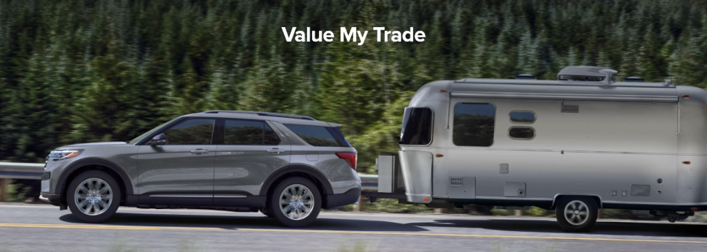 Ford Vehicle with Trailer Attached and Title Saying Value My Trade in white bold letters.