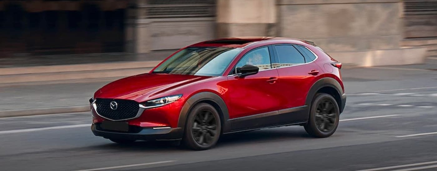 A red 2023 Mazda CX-30 driving in a city.