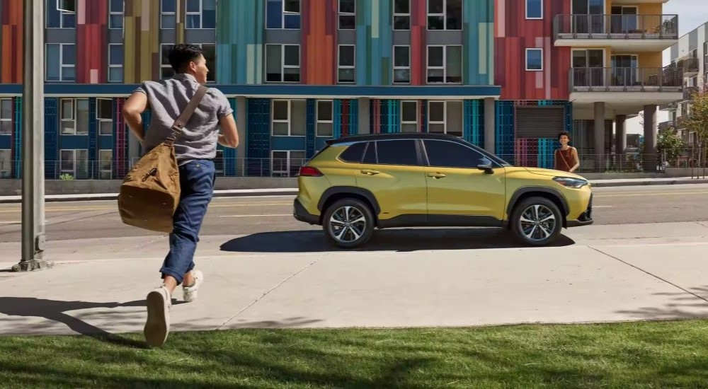 Side of a yellow 2025 Toyota Corolla Cross parked by a curb.