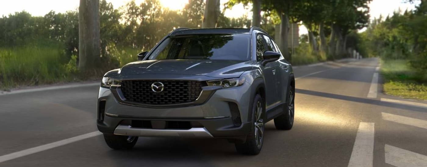 A gray 2025 Mazda CX-50 driving from a Mazda dealer near Doral
