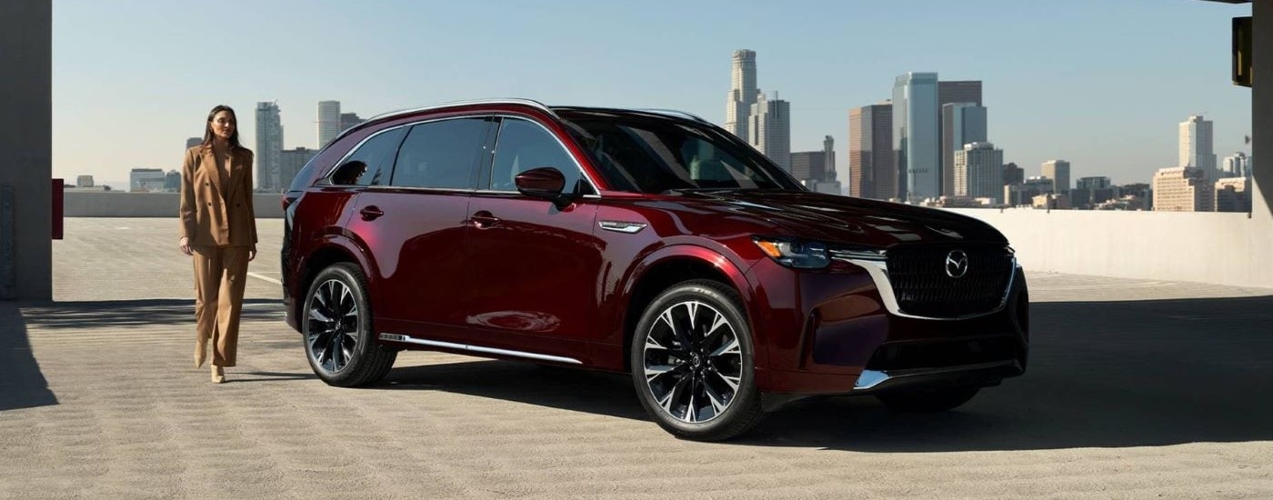 A maroon 2024 Mazda CX-90 parked outside a city