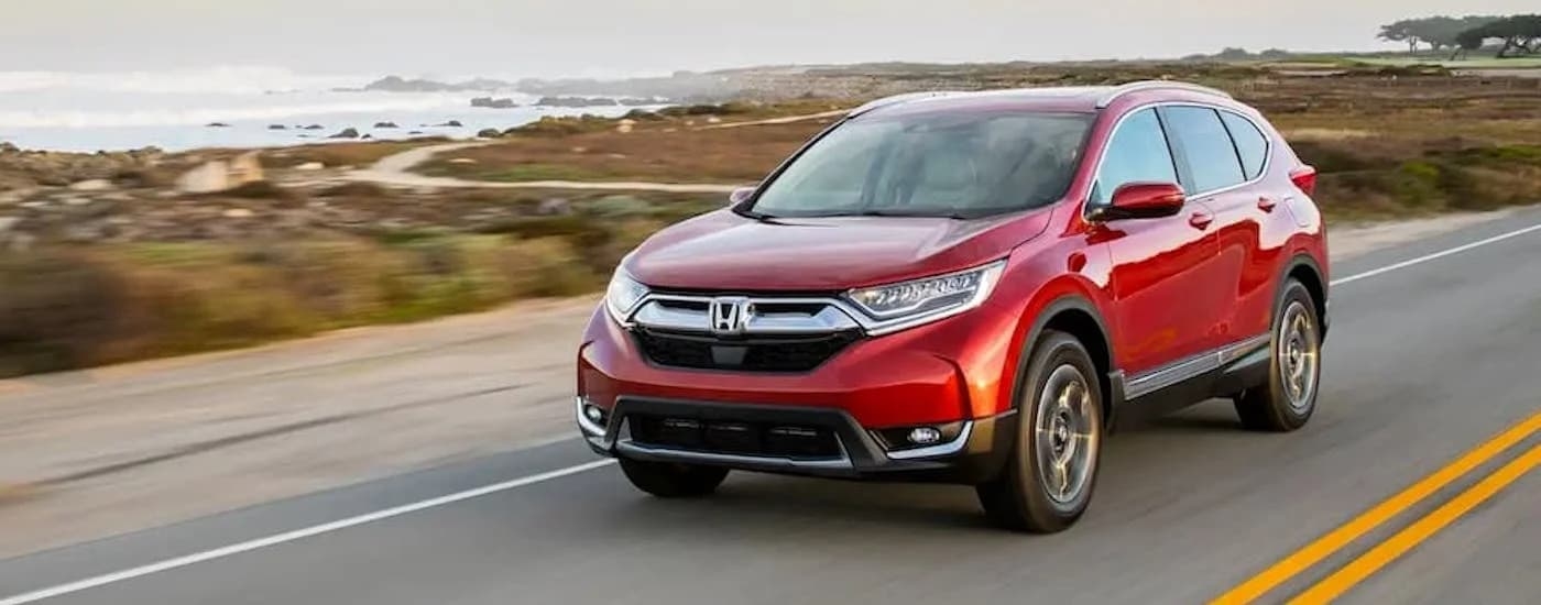 Red used 2018 Honda CR-V for sale near Tenafly driving down an open road.