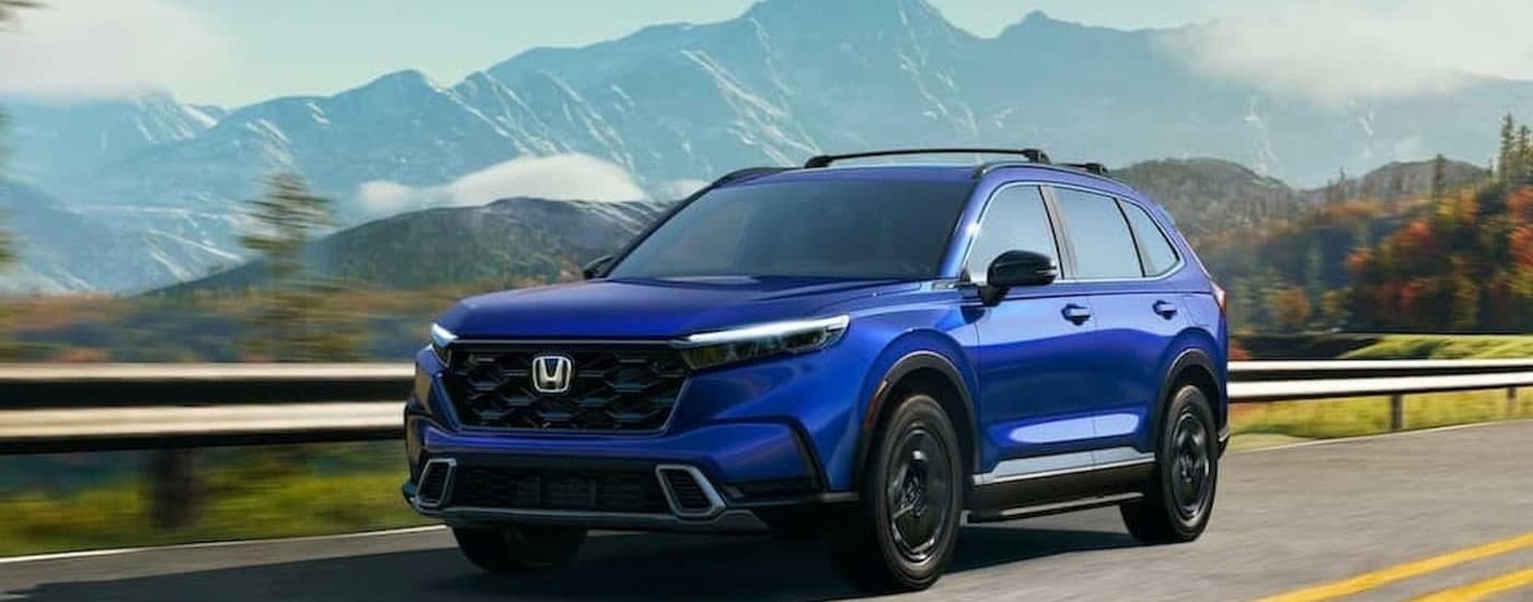 A blue 2026 Honda CR-V Hybrid driving on a highway.
