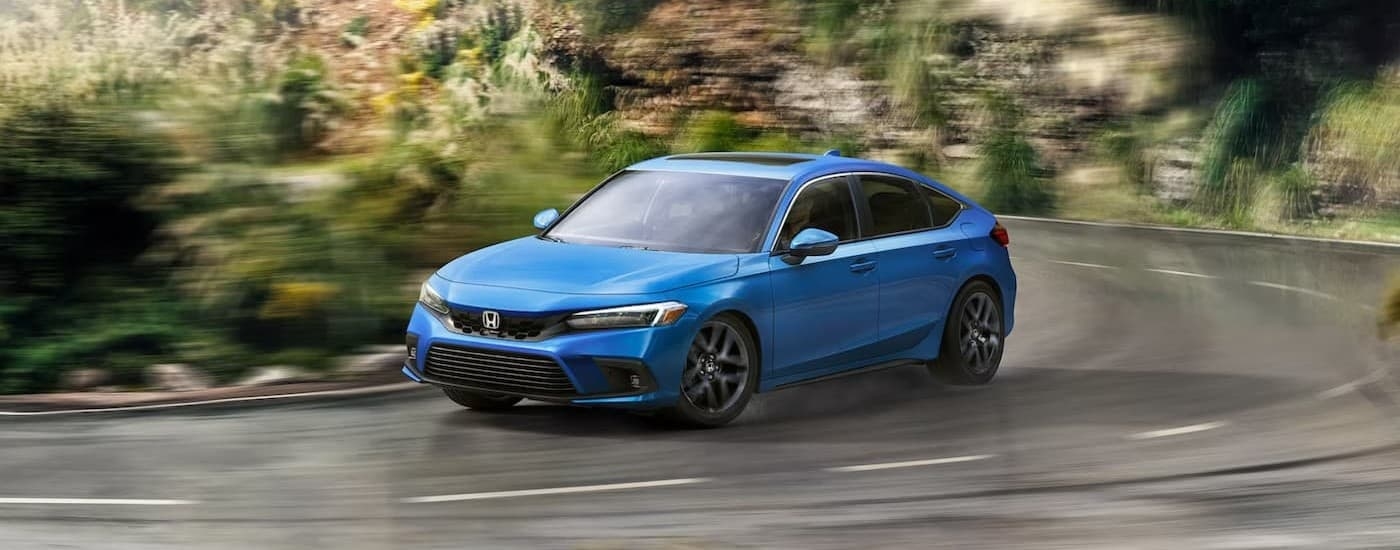 A blue 2024 Honda Civic driving on a highway.