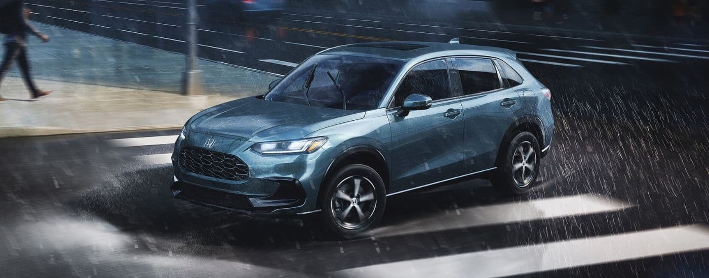 A blue 2025 Honda HR-V driving in the rain.