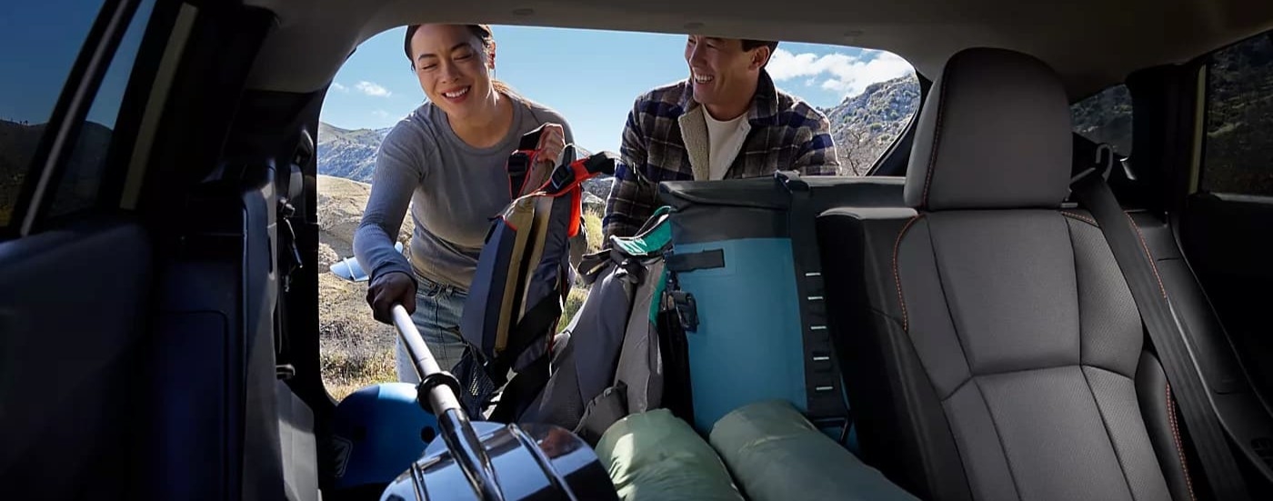 Two people loading cargo in the rear-end of a 2026 Subaru Crosstrek.