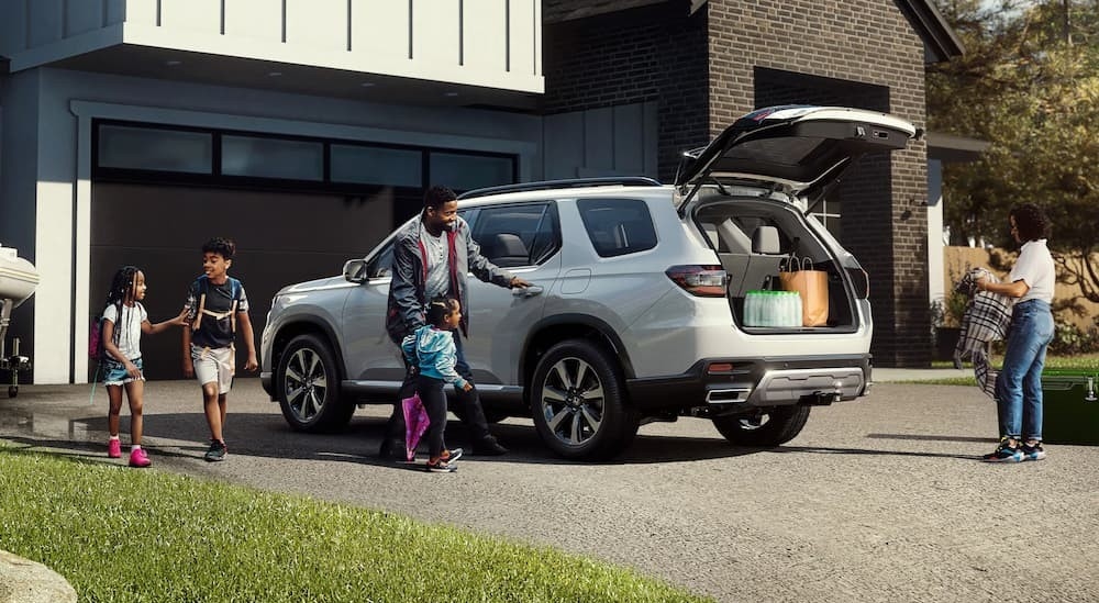 A gray 2025 Honda Pilot parked near a family house.
